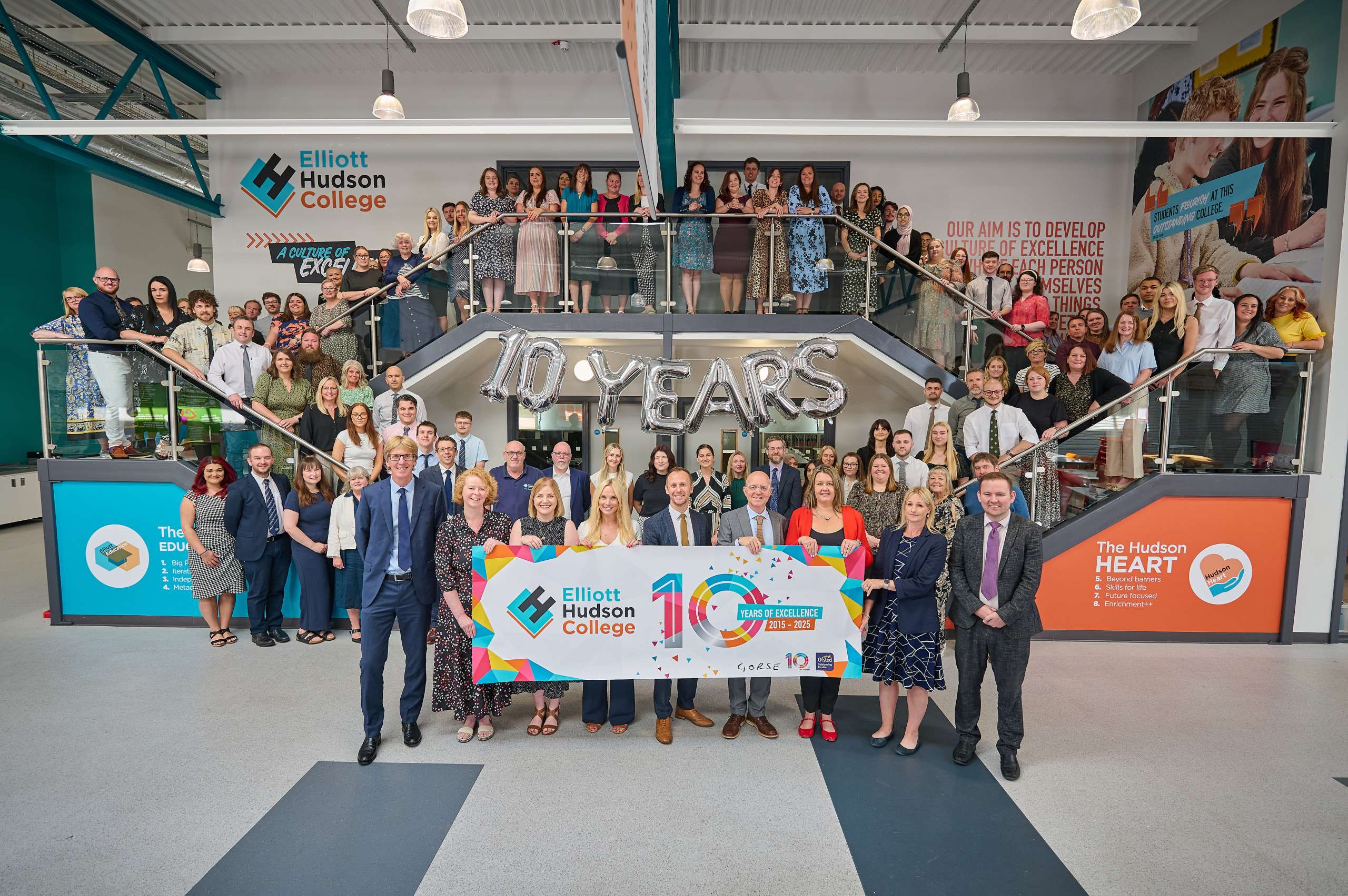 A group photo of all of the staff at EHC, they're holding a banner to celebrate the 10th anniversary of the college